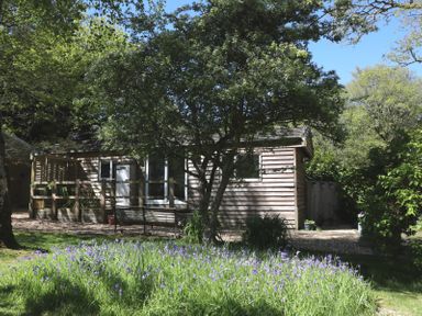 A cabin with a bench and flowers in an outdoor area at Orchard Lodge in Bolney