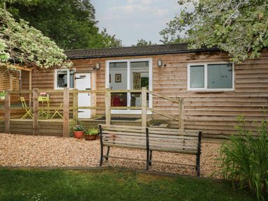 An outdoor area with a wooden cabin and seating at Orchard Lodge in Bolney