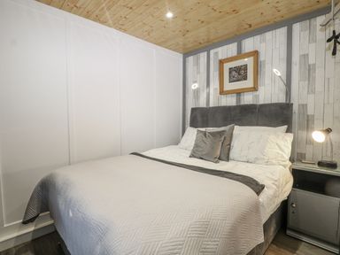 A bedroom with a bed and bedside table at Harvest Lodge in Wineham near Bolney