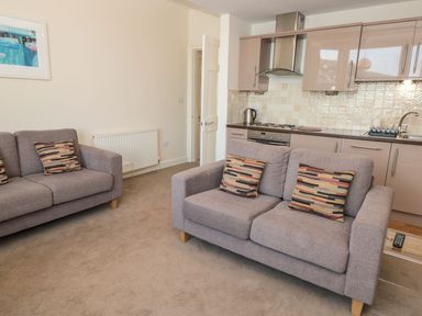 A living area with two gray sofas and a kitchen in the background at 4 Dartview in Dartmouth