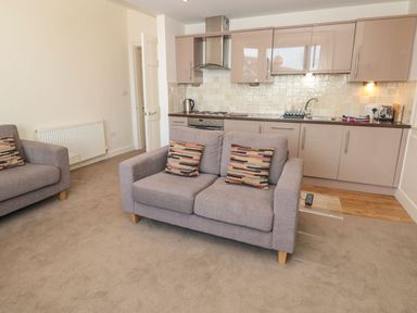 An open living room and kitchen area with two gray sofas with patterned cushions and beige cabinets at 4 Dartview in Dartmouth