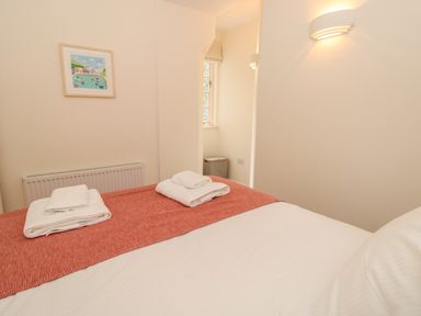 A bedroom with a bed covered in white and red linens and towels on top at 4 Dartview in Dartmouth