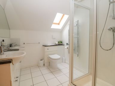 A bathroom with two sinks a toilet a shower and a skylight window at Redwood Retallack in Retallack near St Columb Major