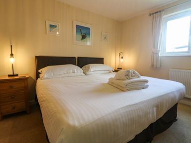 A bedroom with a large bed white linens bedside tables lamps and window at Redwood Retallack Retallack near St Columb Major