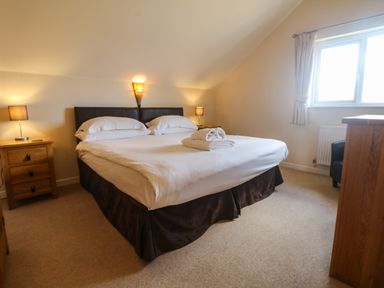 A bedroom with a large bed bedside tables and lamps next to a window at Redwood Retallack in Retallack near St Columb Major