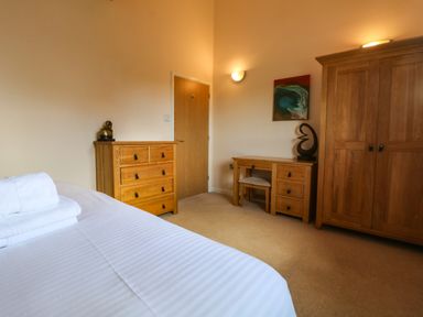 A bedroom with a wooden chest of drawers a wardrobe and a desk with a chair at Redwood Retallack Retallack near St Columb Major