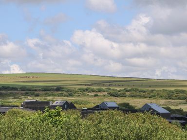 A rural landscape with modern black buildings surrounded by green fields and trees at Redwood Retallack in Retallack near St Columb Major