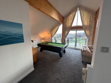 A room with a pool table a sofa large windows with curtains and a balcony at Redwood Retallack in Retallack near St Columb Major
