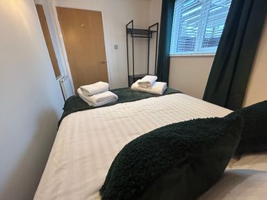 A bedroom with a bed towels on it near a wooden door and window at Redwood Retallack in Retallack near St Columb Major