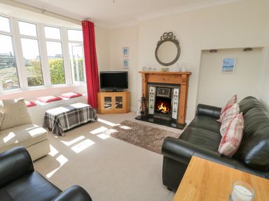 A living room with a fireplace a television sofas and a window seat at The Nook in Benllech