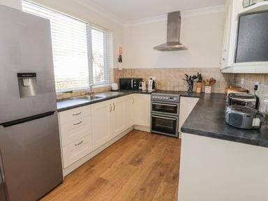 A kitchen with a refrigerator, stove, microwave, toaster, kettle, and countertop appliances at The Nook in Benllech