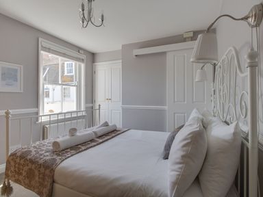 A bedroom with a bed and rolled towels by the window at Harbourside Cottage in Brewers Quay Harbour