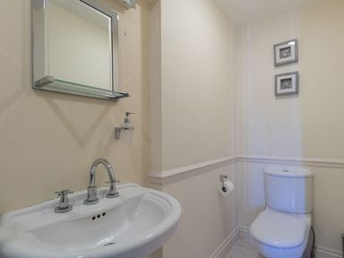 A bathroom with a sink under a mirror and a toilet with two framed pictures above at Harbourside Cottage in Brewers Quay Harbour