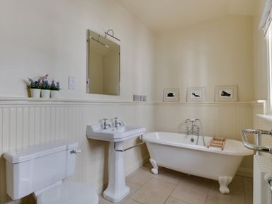 A bathroom with a toilet sink bathtub and framed pictures on the wall at Harbourside Cottage in Brewers Quay Harbour