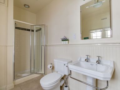 A bathroom with a toilet sink mirror and a glass shower at Harbourside Cottage Brewers Quay Harbour