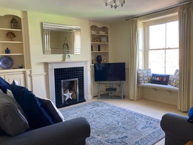 A living room with a fireplace a television and a window seat at Harbourside Cottage Brewers Quay Harbour
