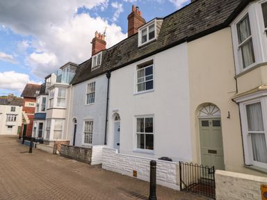 A street view of terraced houses with chimneys along a paved road at Harbourside Cottage in Brewers Quay Harbour