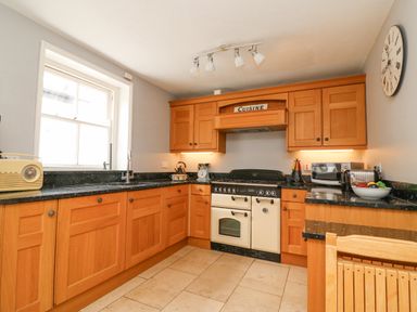 A kitchen with wooden cabinets a stove a radio and a fruit bowl at Harbourside Cottage in Brewers Quay Harbour