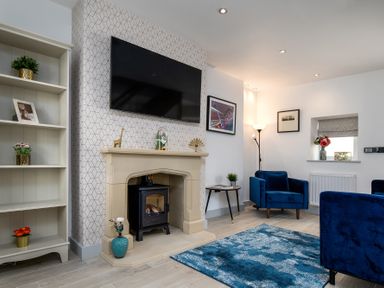 A living room with a fireplace a television blue chairs and a blue rug at The Old Sweet Shop in Conwy