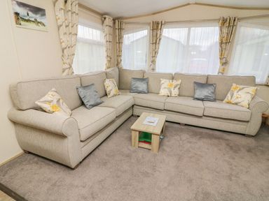 A living room with a large beige corner sofa and small wooden coffee table at 12A Borwick Lakes South Lakeland Leisure Village