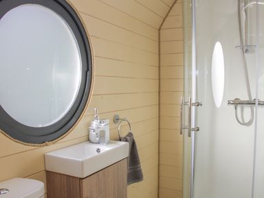 A bathroom with a round window sink with soap dispenser towel ring and shower at Stapeley Pod in White Grit near Chirbury