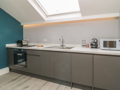 A kitchen with built in oven toaster kettle microwave and sink under a skylight at New Inn Apartment Tholthorpe near Easingwold