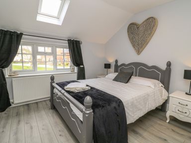 A bedroom with a gray bed and white bedding near a window with black curtains at New Inn Apartment in Tholthorpe near Easingwold