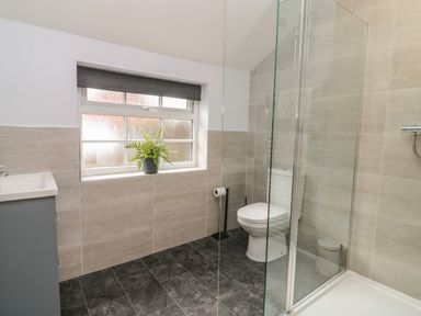 A bathroom with a toilet sink shower and window with a plant on the sill at New Inn Apartment in Tholthorpe near Easingwold