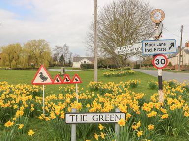 A road junction with multiple road signs and yellow flowers at New Inn Apartment in Tholthorpe near Easingwold