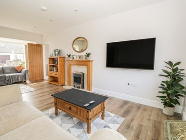 A living room with wooden furniture a wall-mounted TV a fireplace and a potted plant at The Croft Bungalow Plumbland near Aspatria