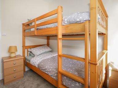 A bedroom with a wooden bunk bed and a small table with a lamp at The Croft Bungalow in Plumbland near Aspatria