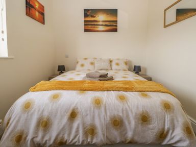 A bedroom with a bed yellow patterned duvet towels on bed and sunset pictures on walls at The Croft Bungalow in Plumbland near Aspatria