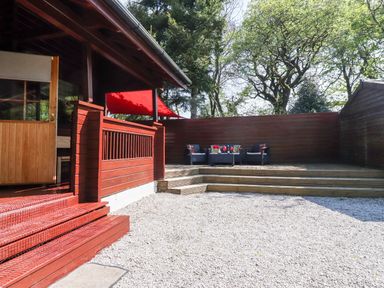 An outdoor patio area with wooden steps and decking with chairs and a table at Gisburn Forest Lodge in Tosside near Wigglesworth