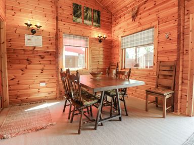 A dining area with a wooden table and six chairs in a wooden paneled room at Gisburn Forest Lodge Tosside near Wigglesworth