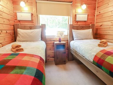 A bedroom with two single beds and a nightstand with a lamp between them at Gisburn Forest Lodge Tosside near Wigglesworth