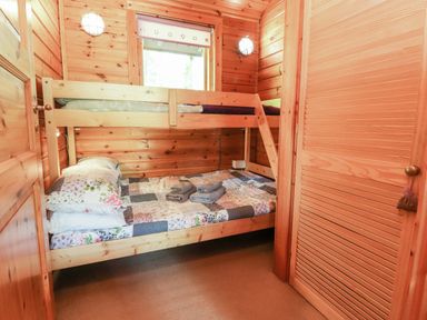 A wooden bedroom with bunk beds two folded towels on the bottom bed and a window at Gisburn Forest Lodge Tosside near Wigglesworth