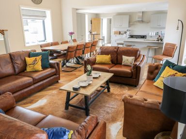 A living room with brown leather sofas and a wooden dining table at Pheasant's Roost in Lelley near Burton Pidsea