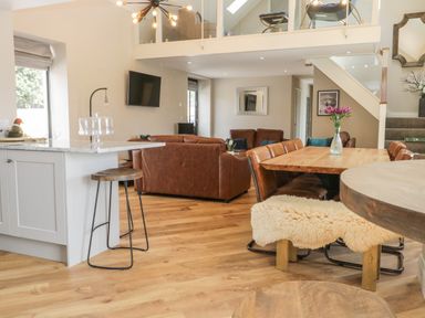 An open plan living room and dining area with brown leather sofas a wooden dining table and stools at Pheasant's Roost in Lelley near Burton Pidsea