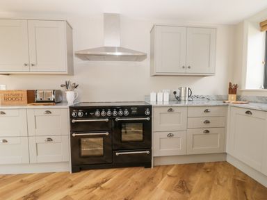 A kitchen with gray cabinets a black stove a toaster and a kettle at Pheasant's Roost in Lelley near Burton Pidsea