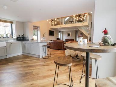 An open kitchen and living room with wooden floors stools and a loft area at Pheasant's Roost in Lelley near Burton Pidsea