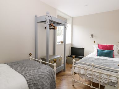 A bedroom with two beds a window and a grey clothing rack with boxes at Pheasant's Roost in Lelley near Burton Pidsea