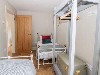 A bedroom with two single beds a wooden door and a gray open wardrobe with hangers and a storage box at Pheasant's Roost in Lelley near Burton Pidsea
