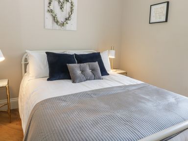 A bedroom with a bed, bedside tables, lamps, and wall decorations at Pheasant's Roost in Lelley near Burton Pidsea