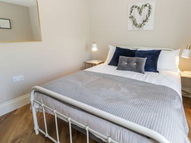 A bedroom with a white metal bed frame pillows and bedside tables with lamps at Pheasant's Roost in Lelley near Burton Pidsea