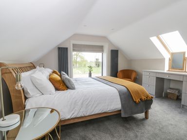 A bedroom with a bed and pillows a side table with a lamp a window a chair and a dressing table at Pheasant's Roost in Lelley near Burton Pidsea