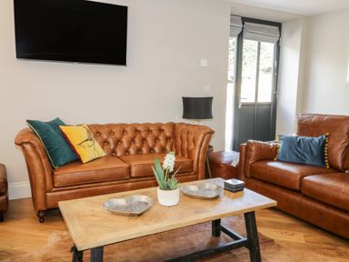 A living room with two leather sofas a wooden coffee table and a wall mounted television at Pheasant's Roost in Lelley near Burton Pidsea