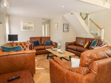 A living room with brown leather sofas a wooden coffee table and stairs at Pheasant's Roost in Lelley near Burton Pidsea