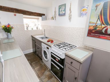 A kitchen with a gas stove washing machine dishwasher and flowers in a jug at The Lodge in Stainsacre near Whitby