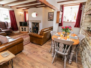A living and dining area with brown leather sofas a wooden dining table set with breakfast and a fireplace at The Lodge in Stainsacre near Whitby