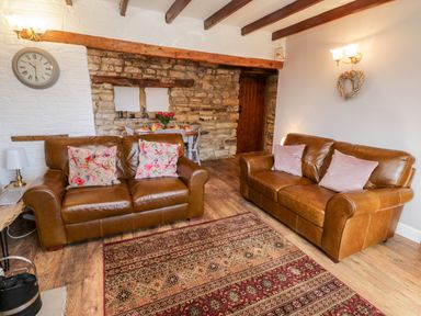 A living room with two brown leather sofas and a patterned rug at The Lodge in Stainsacre near Whitby